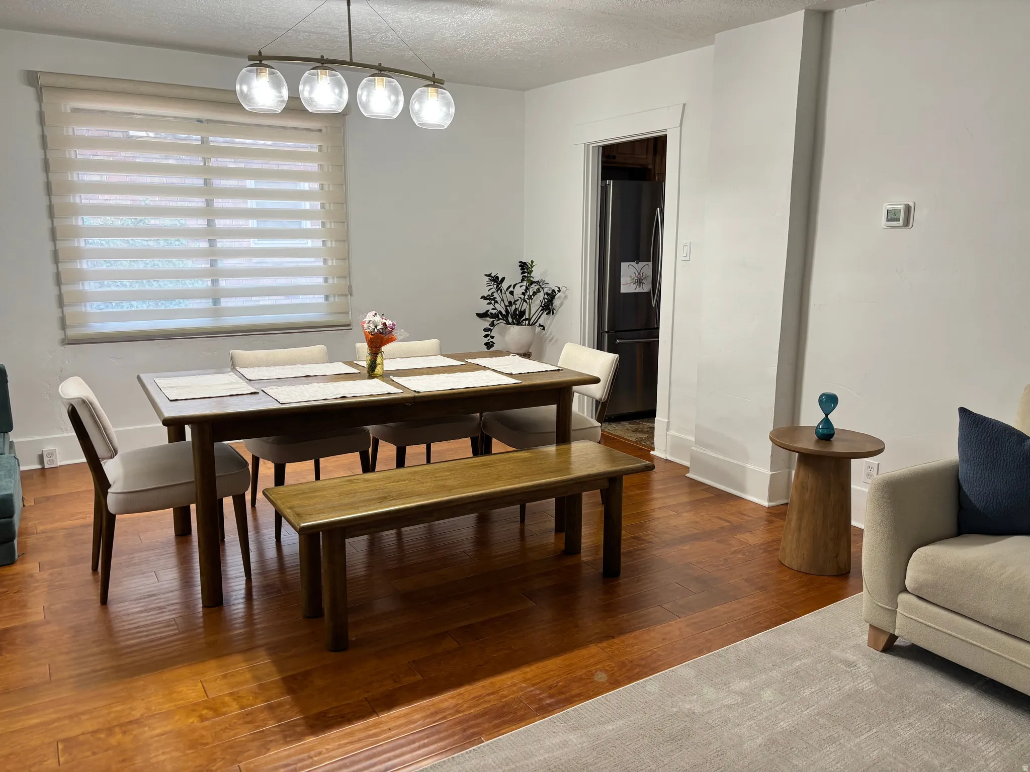 Hardwood flooring throughout, recessed lighting fixture, white walls with detailed trim, and a window with horizontal blinds