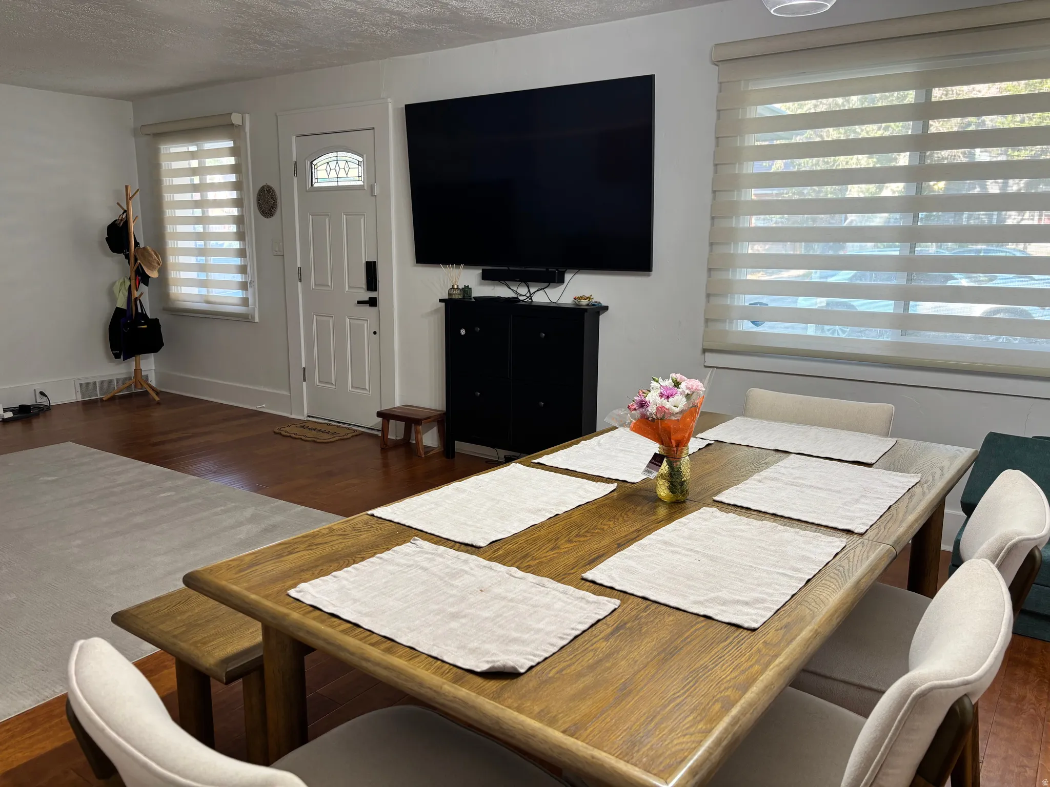 Wood-finish flooring throughout, white walls, and a white entry door with decorative glass
