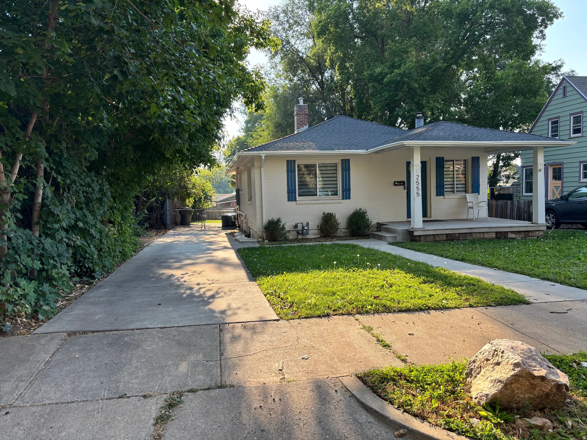 Cream exterior with blue shutters, covered porch, and a concrete driveway