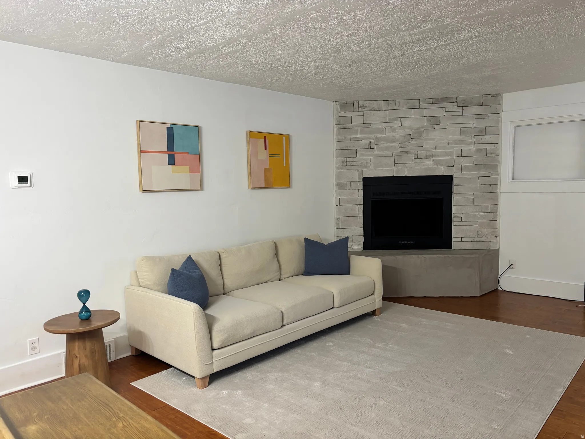 Corner fireplace featuring a stone-clad facade, black firebox, and concrete hearth