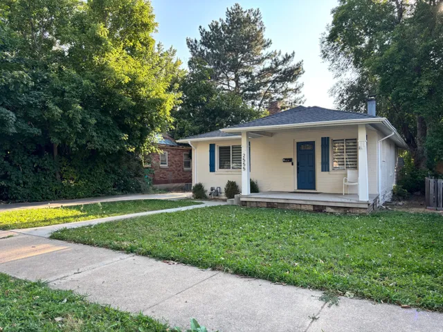 Cream-colored exterior with a covered front porch, a blue entry door, and blue window shutters