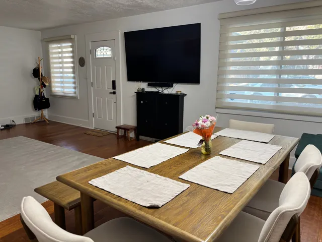 Wood-finish flooring throughout, white walls, and a white entry door with decorative glass