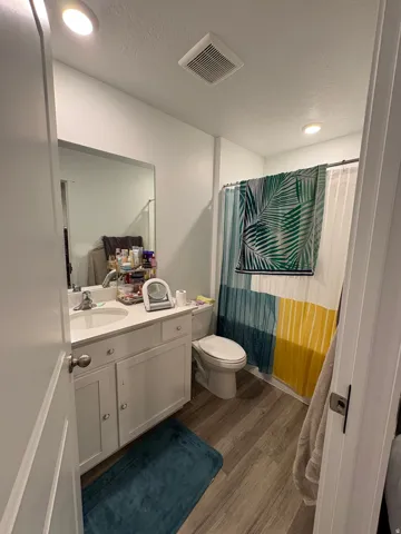 White vanity with integrated sink, wood-finish flooring, and recessed ceiling lighting