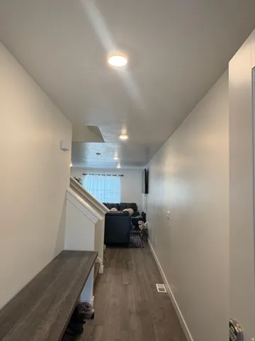 Recessed lighting, wood-finish flooring, white painted walls, white staircase, built-in storage bench