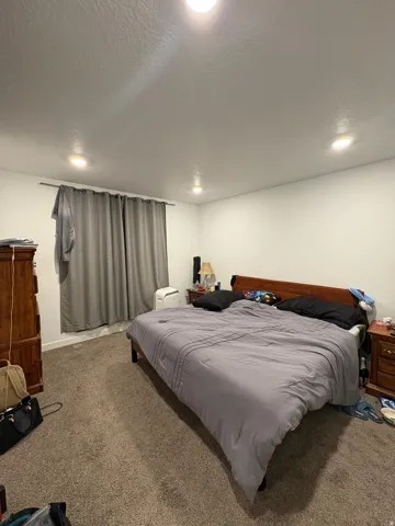 Recessed ceiling lighting illuminates a room with light-colored walls and carpet flooring