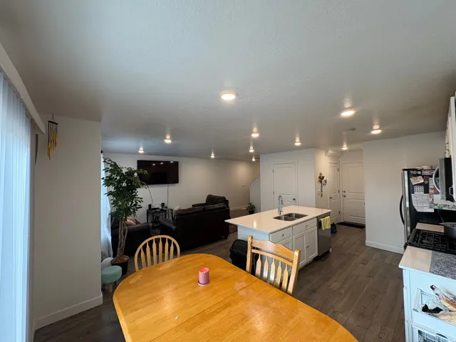 Kitchen and living area featuring recessed lighting, a kitchen island with sink, stainless steel dishwasher, and wood-finish flooring