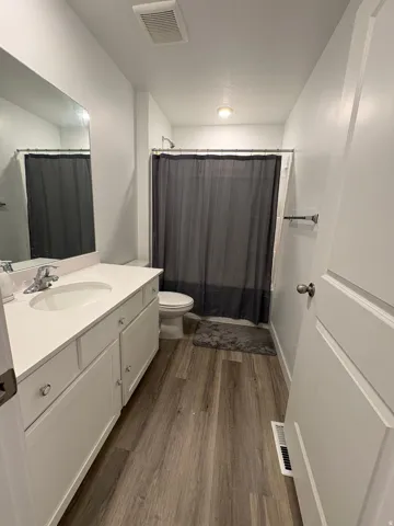 White vanity with an integrated sink, polished chrome faucet, and wood-finish flooring