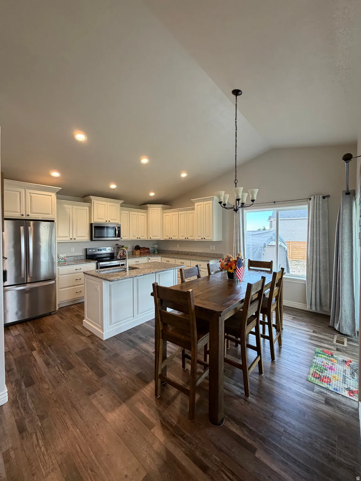 Dining off of kitchen with large windows and sliding glass door to covered patio and backyard. featuring  LVP flooring, and vaulted ceiling