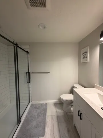 Basement Bath: featuring large walk-in Shower with subway tile and black-framed glass sliding doors.