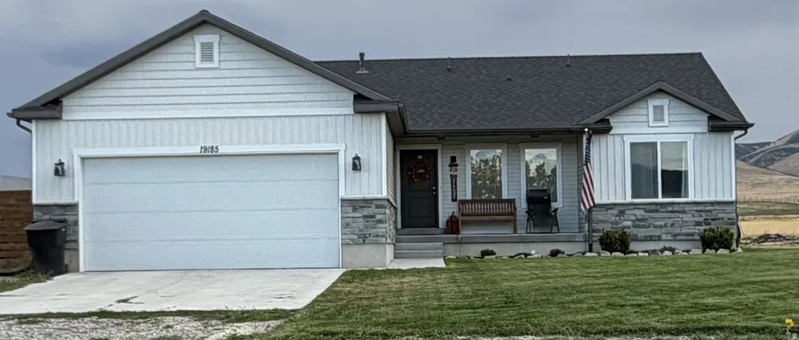 Single-story residence featuring light-colored siding, a dark shingle roof, and a stone facade accent, 2 car garage