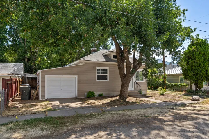 Siding exterior with a dormer window, attached garage, concrete driveway, and mature trees