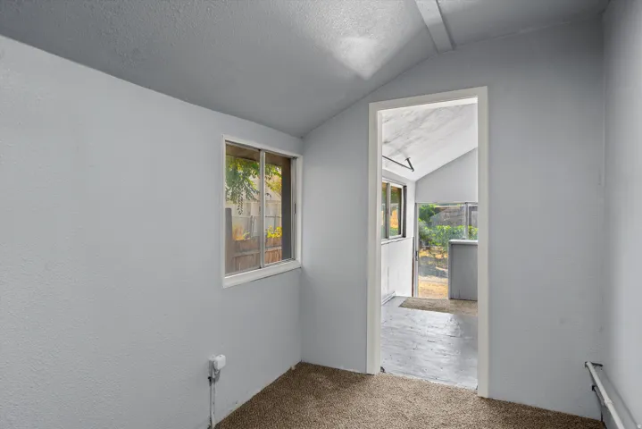Interior space featuring a vaulted ceiling and an exterior-facing window