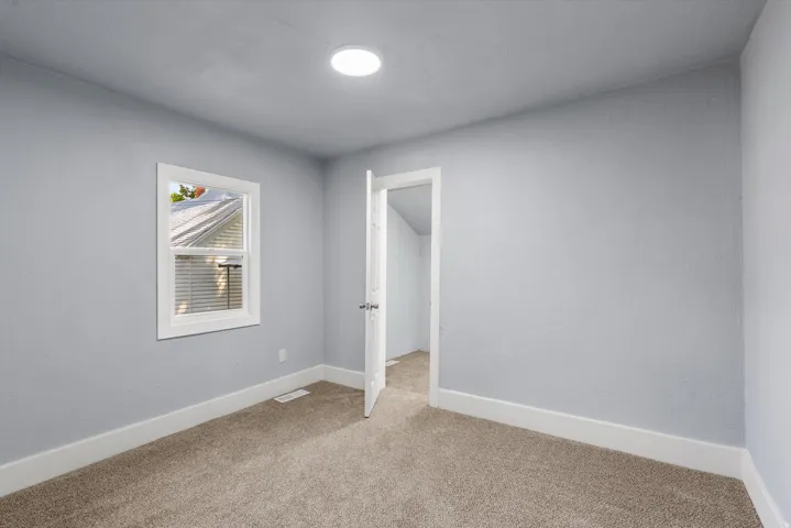 Recessed ceiling light, neutral-toned carpet, light-colored walls, white trim, and a single window