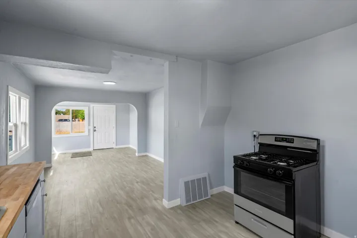 Modern kitchen featuring stainless steel gas range with convection oven, wood-finish plank flooring, white cabinetry, and recessed ceiling lighting