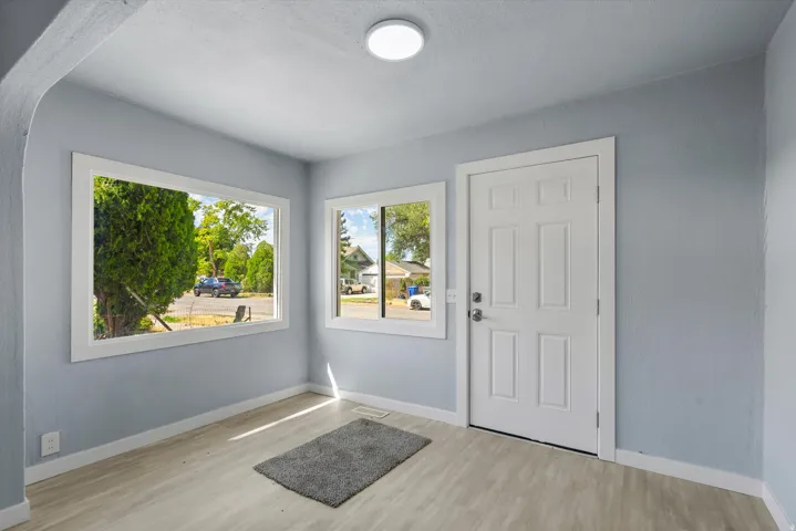 Entryway featuring wood-finish flooring, light blue wall finishes, white trim, and a paneled entry door