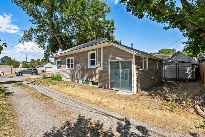 Gable roofline, horizontal siding, white trim, sliding glass door, and alley