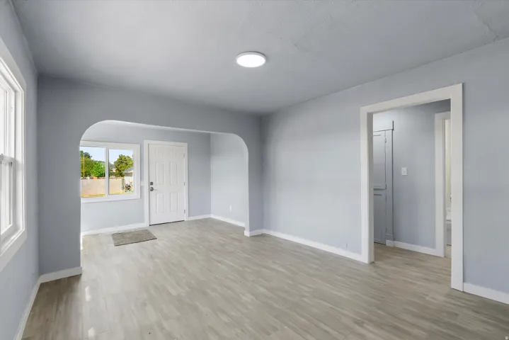 Wood-finish flooring, recessed lighting, arched doorway, paneled entry door, and white trim throughout