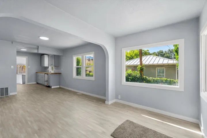 Expansive room with wood-finish flooring, light blue wall paint, multiple windows, and recessed lighting