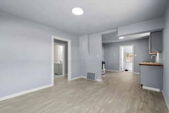 Wood-finish flooring throughout, with flush-mount ceiling lights, and light gray cabinetry with wood countertops in the kitchen area