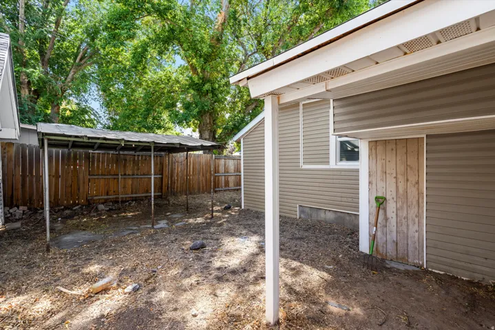 Outdoor storage shed, wood privacy fencing, covered patio, and mature trees