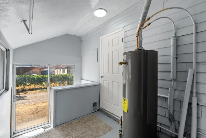 Utility area with water heater, exterior door, and sliding glass door