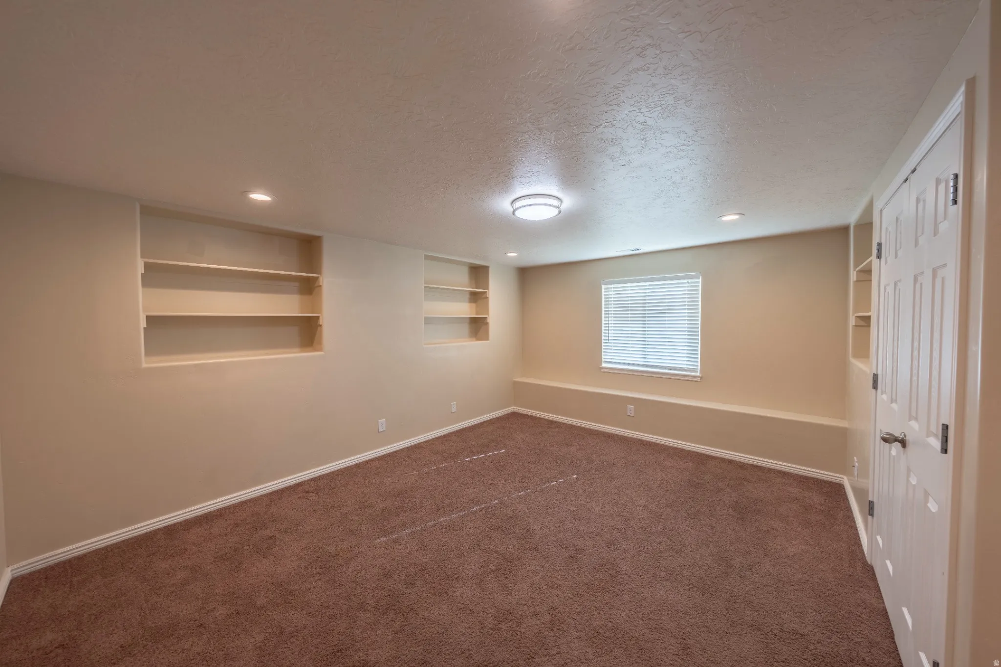 Built-in shelving, recessed lighting, ceiling-mounted light fixture, window with blinds, panel door