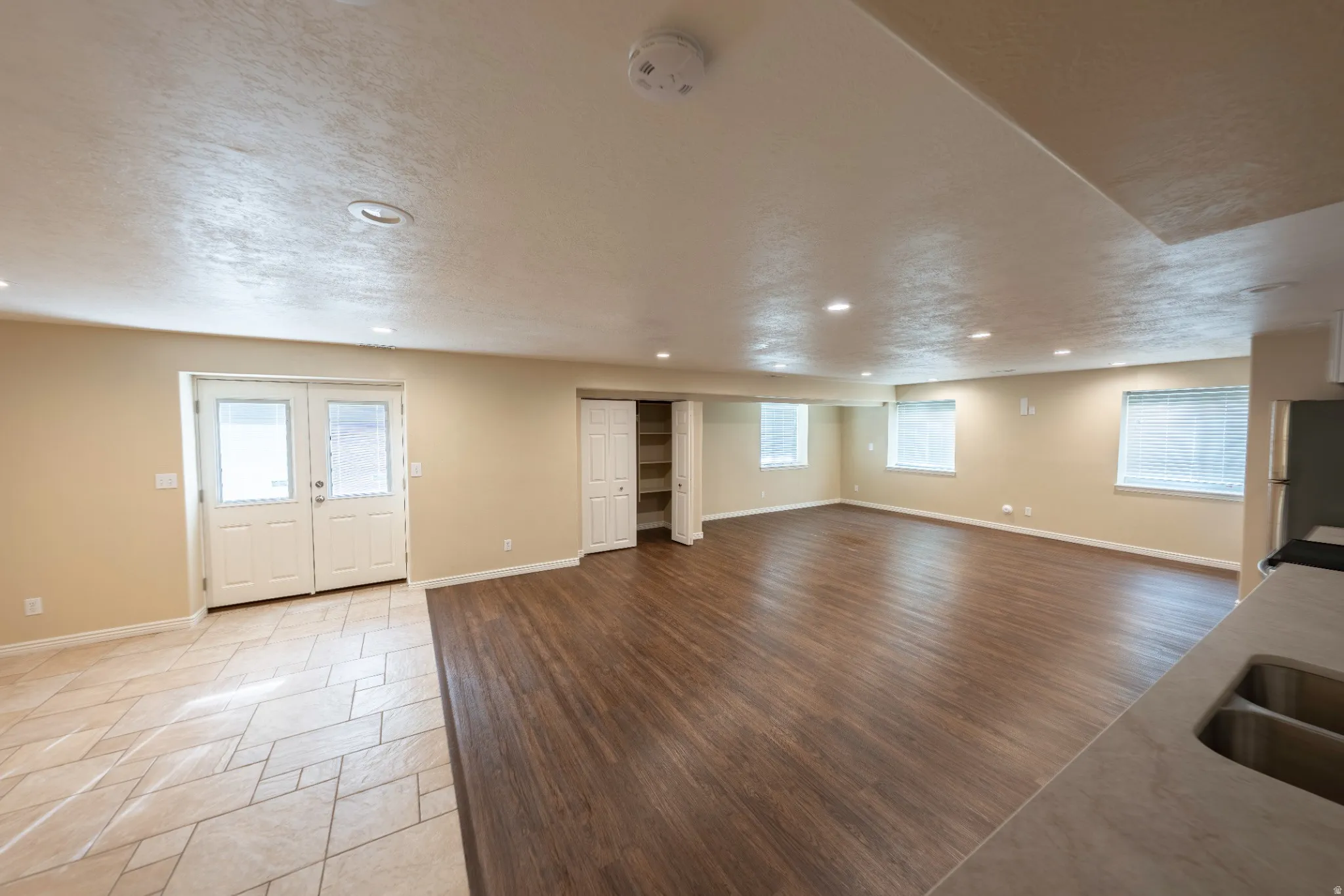 Recessed lighting illuminating a spacious room with wood-finish flooring and multiple windows