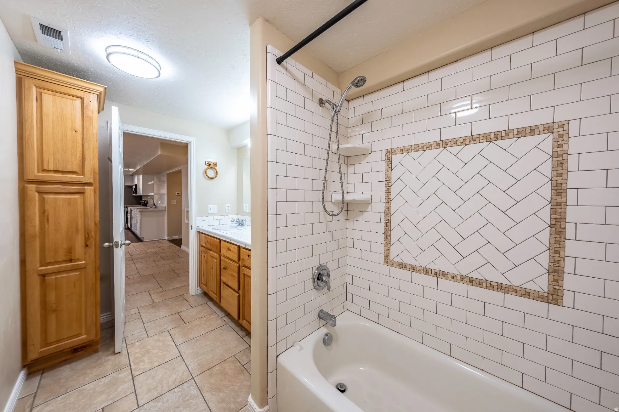 Bathtub with subway tile surround, decorative tile accent, and built-in shelving