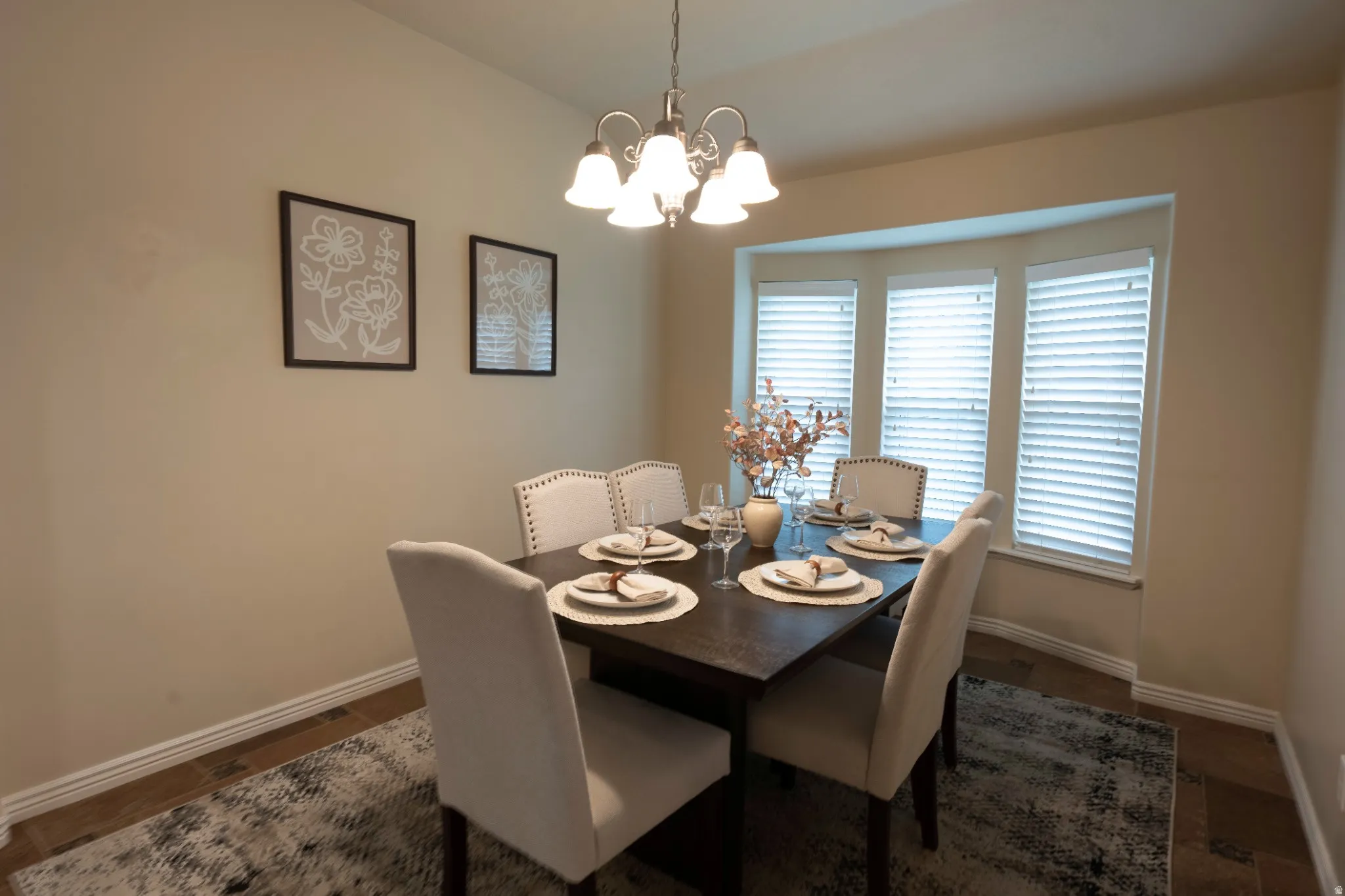 Bay window with blinds, overhead chandelier, and wood-finish flooring