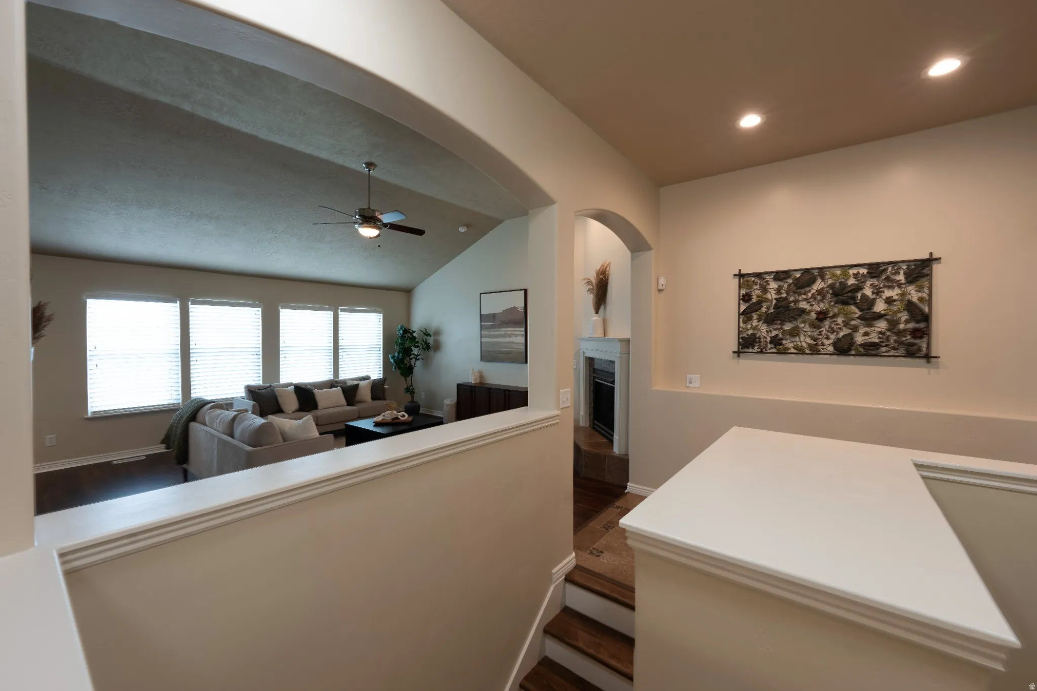 Vaulted ceiling in living area, wood-finish flooring, multiple windows with blinds, recessed lighting, and a built-in fireplace
