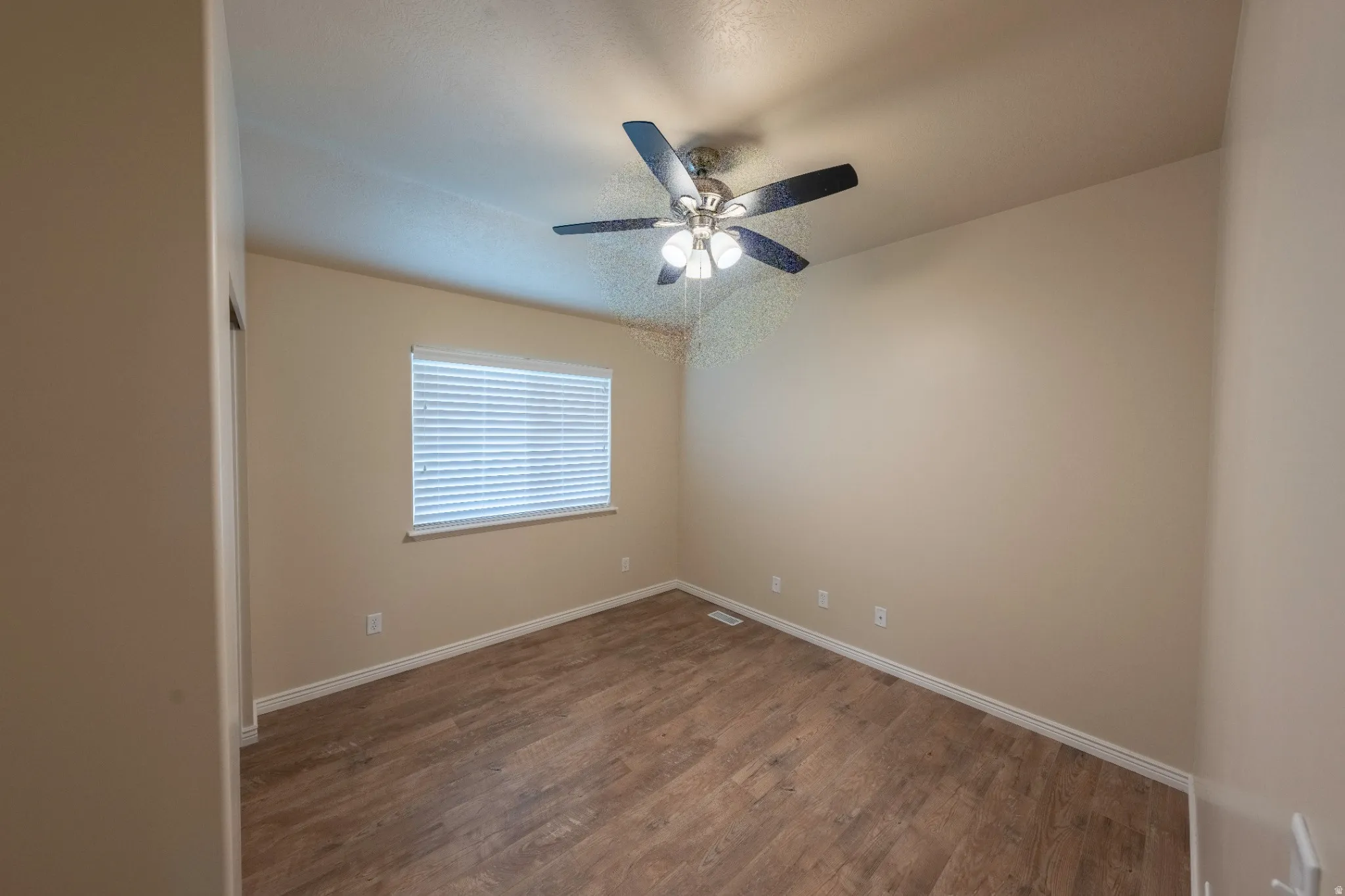 Wood-finish flooring, neutral wall tones, and a ceiling fan with integrated lighting