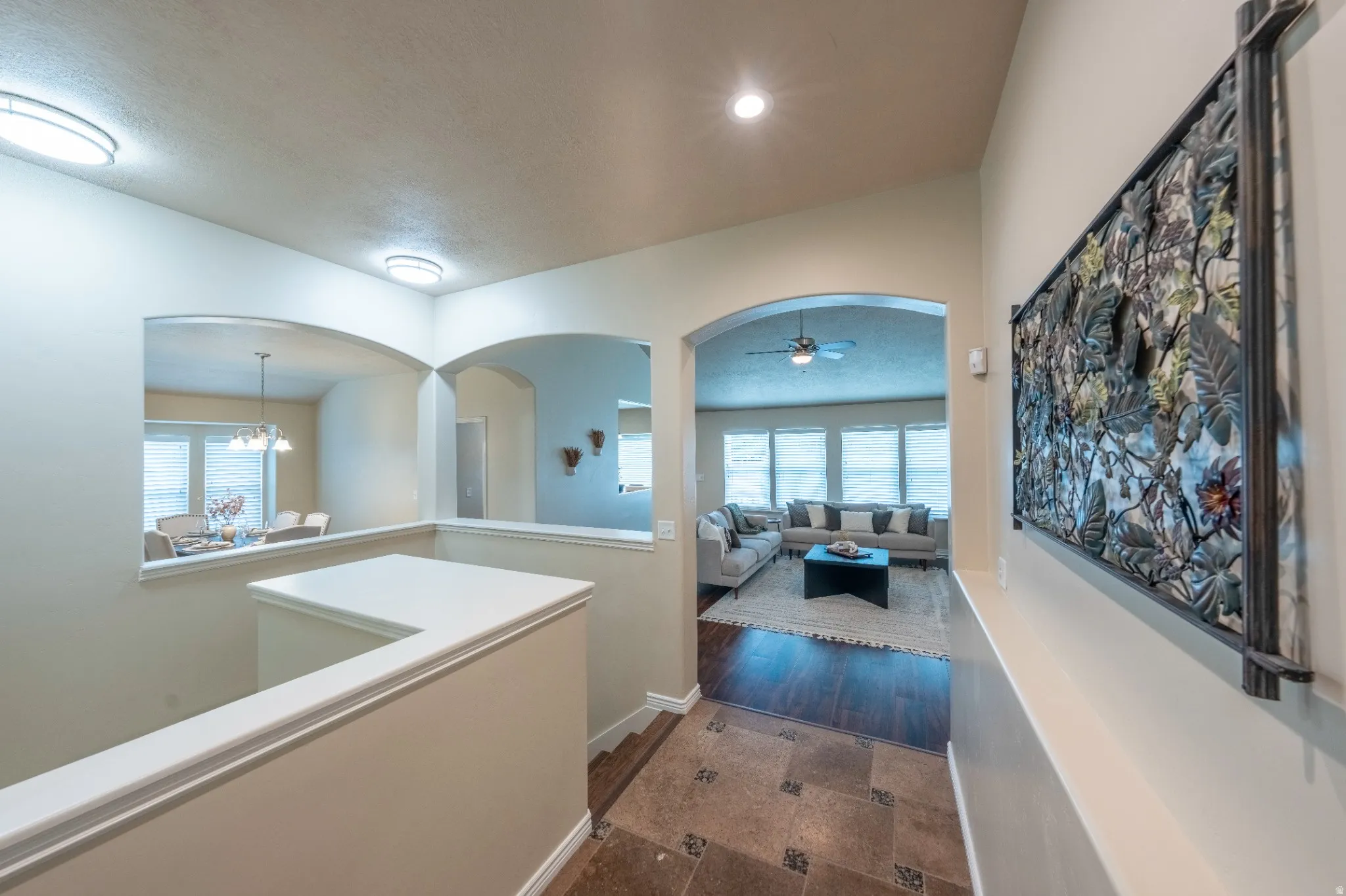 Archways providing open sightlines, recessed lighting, tile flooring with decorative inserts, wood-finish flooring, and a ceiling fan