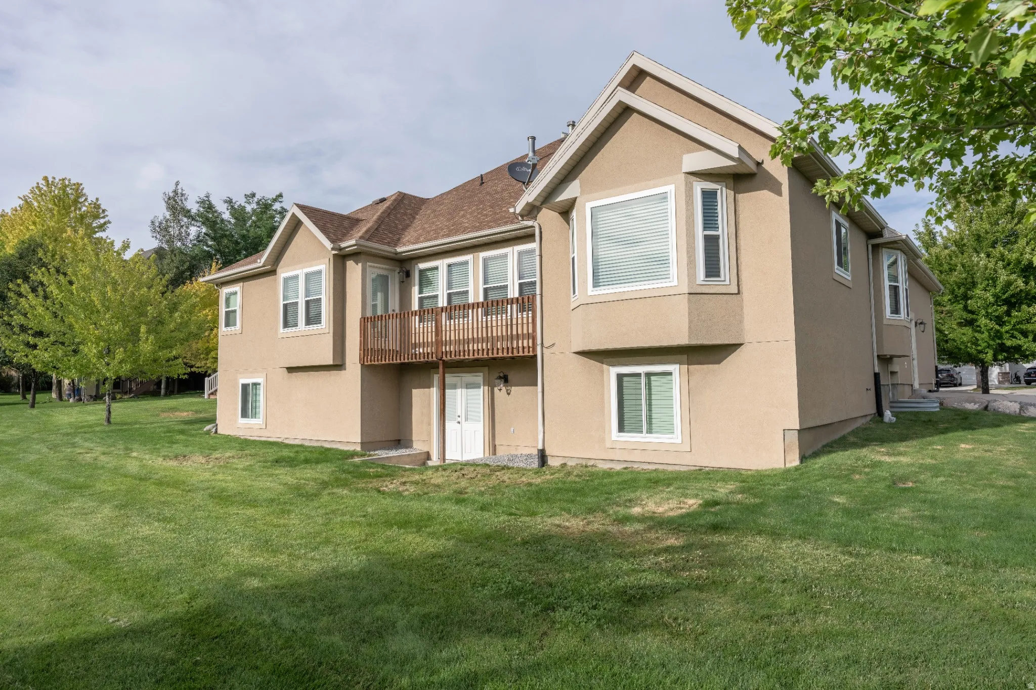 Stucco exterior featuring multiple windows and a brown wood-finish deck