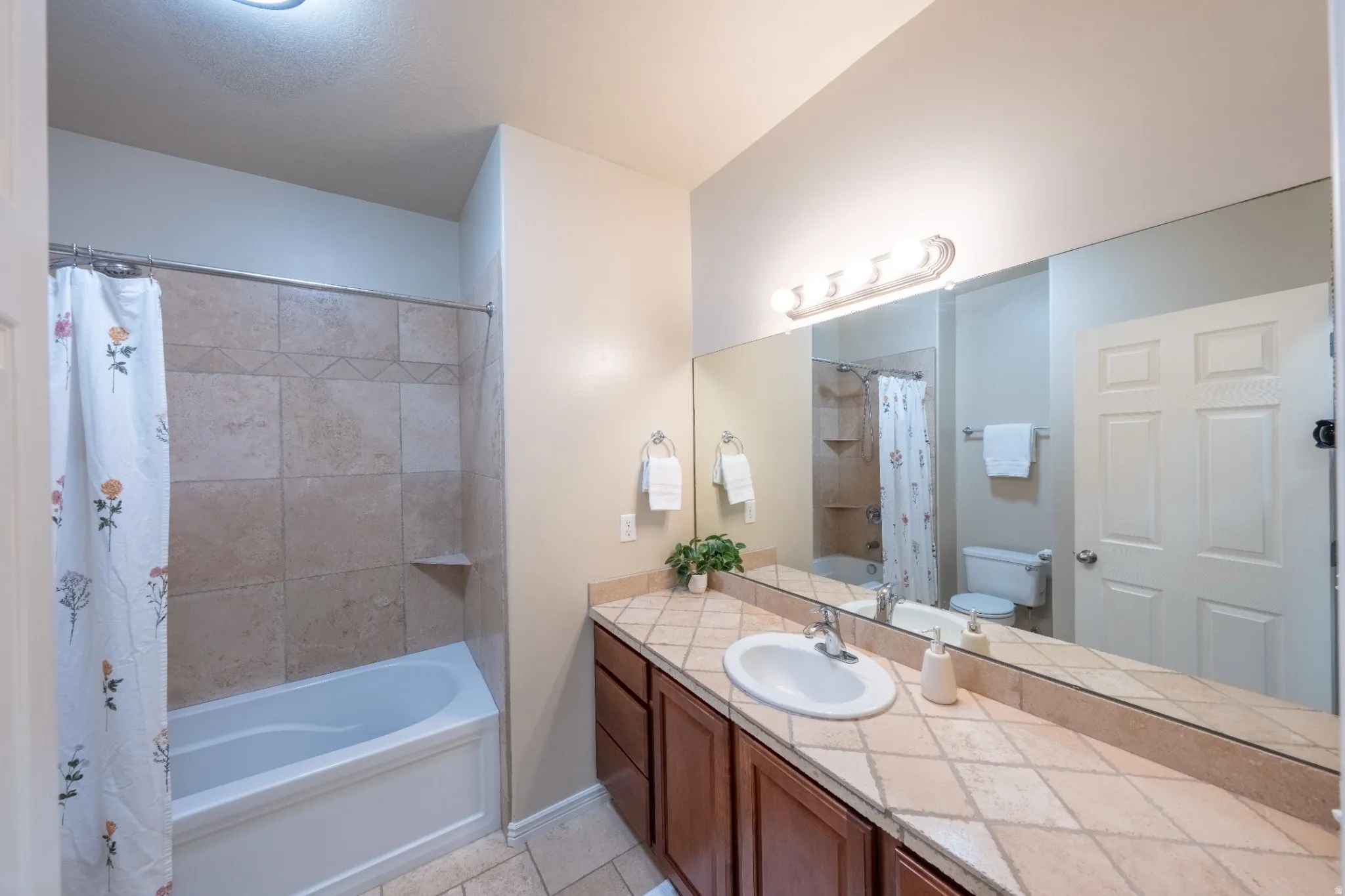 Spa-inspired master bathroom featuring a double vanity with wood cabinetry, ceramic tile countertops, and an undermount sink