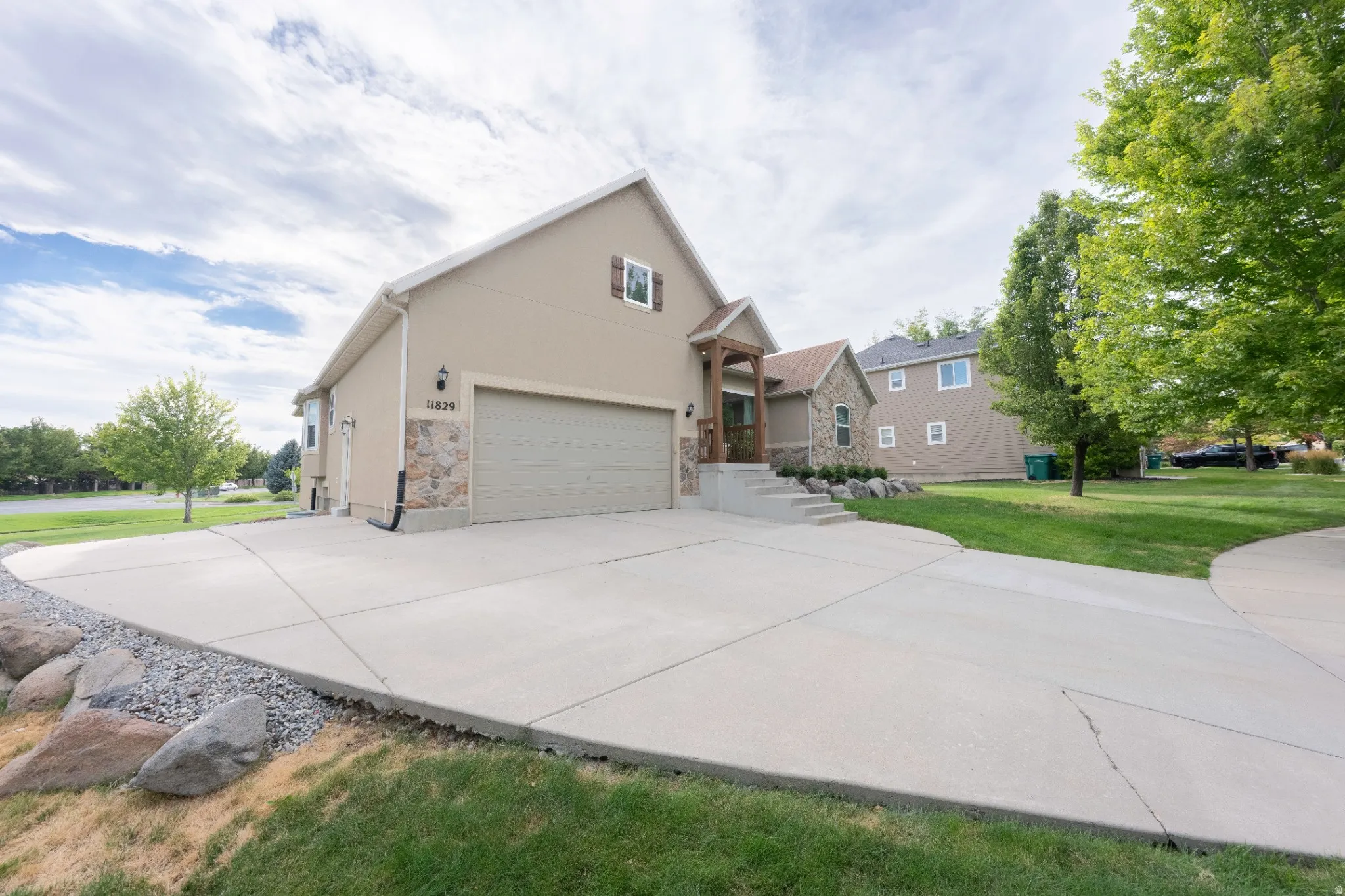 Exterior featuring a stone and stucco facade, two-car garage, concrete driveway, and front entry with wood columns