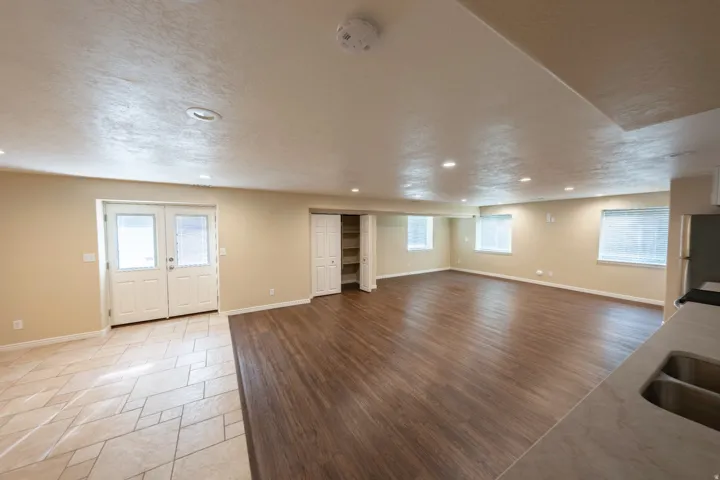 Recessed lighting illuminating a spacious room with wood-finish flooring and multiple windows