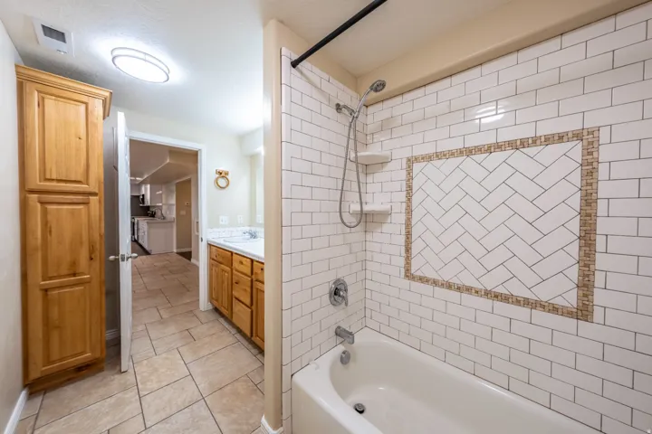 Bathtub with subway tile surround, decorative tile accent, and built-in shelving