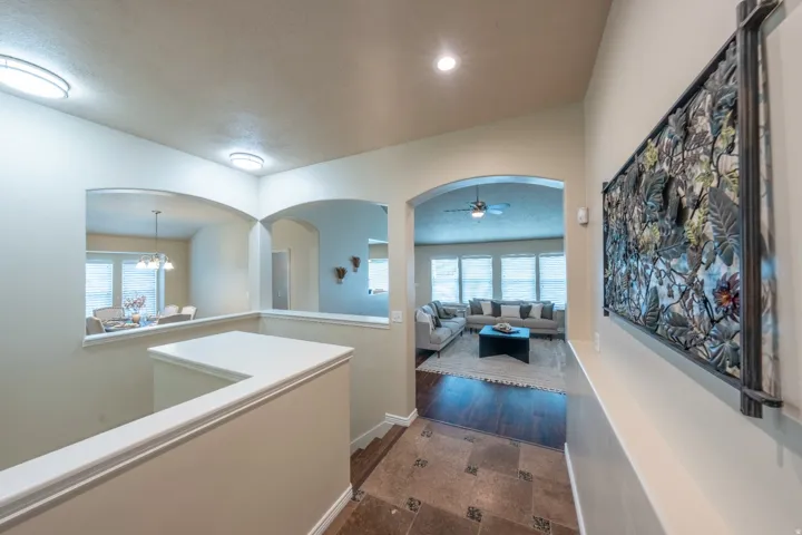 Archways providing open sightlines, recessed lighting, tile flooring with decorative inserts, wood-finish flooring, and a ceiling fan