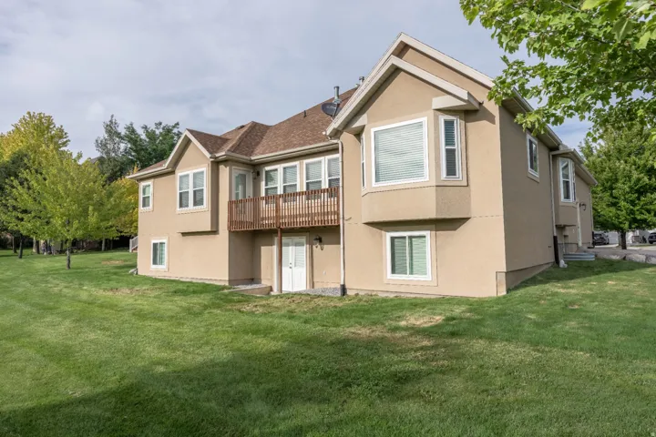 Stucco exterior featuring multiple windows and a brown wood-finish deck