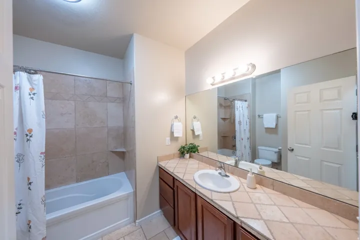 Spa-inspired master bathroom featuring a double vanity with wood cabinetry, ceramic tile countertops, and an undermount sink