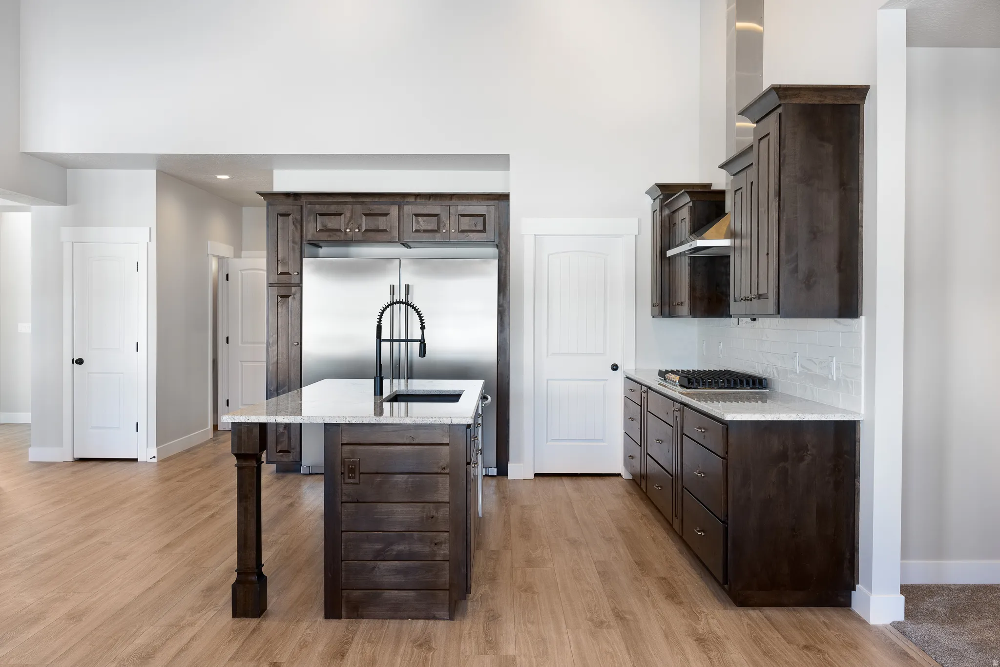 Kitchen featuring wood-finish flooring, dark wood cabinetry, white subway tile backsplash, and stainless steel appliances