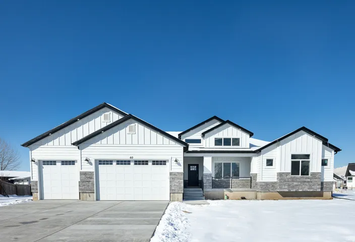 Modern farmhouse-inspired exterior with white vertical and horizontal siding, stone accents, and dark trim