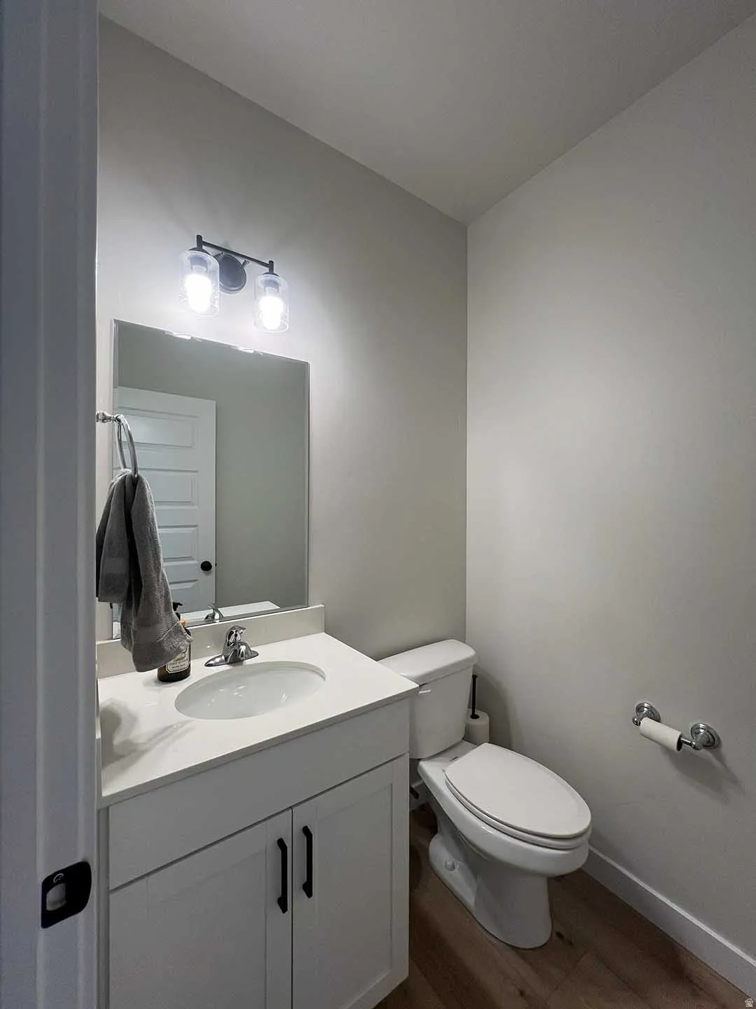 White vanity with a single basin sink, chrome faucet, and black hardware