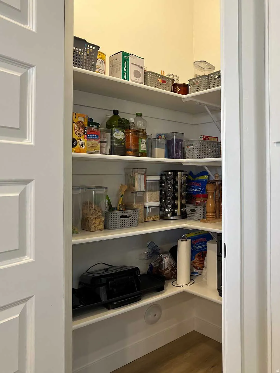 Walk-in pantry featuring white shelving, wood-finish flooring, and white trim