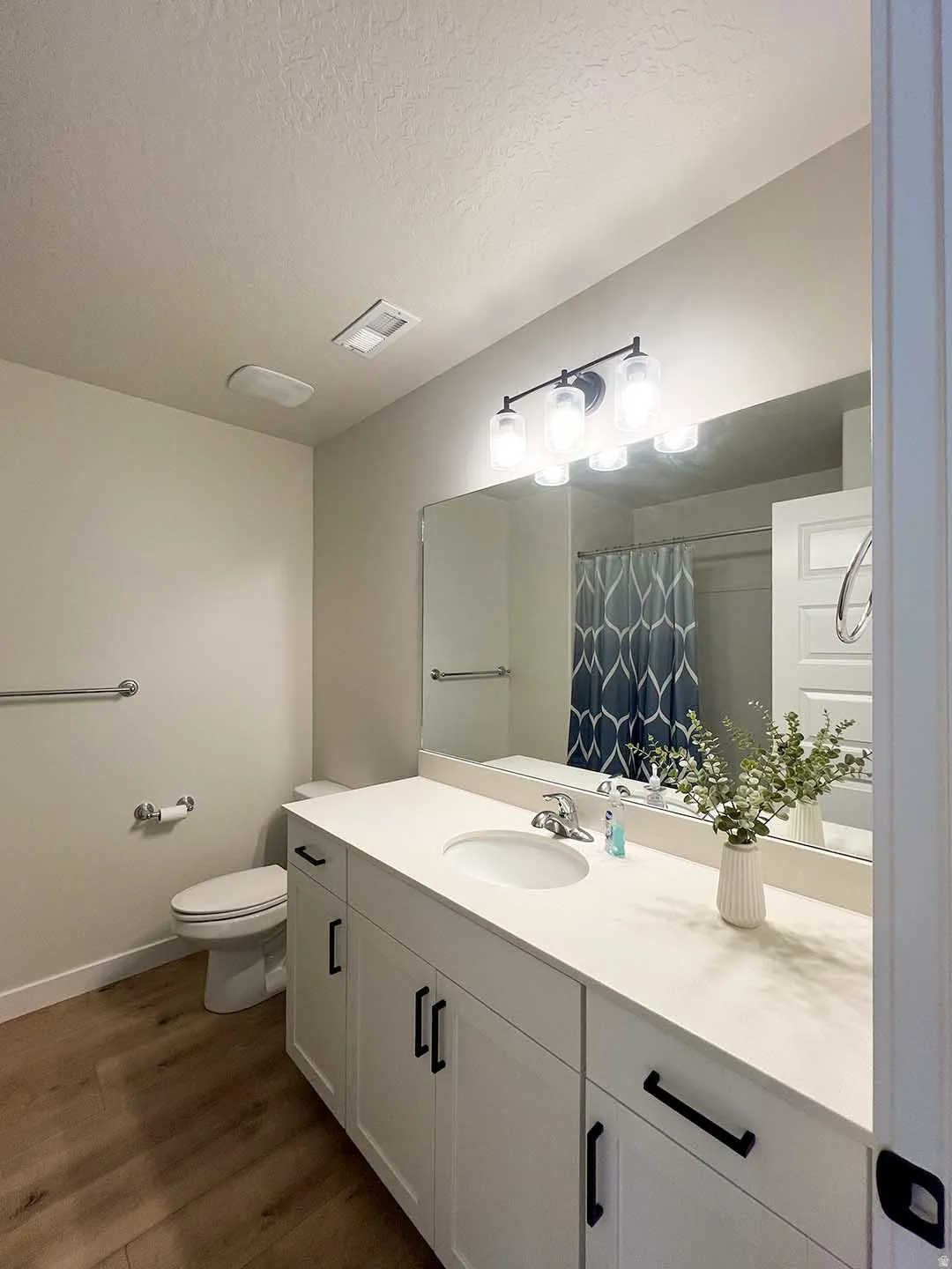 White vanity with black pulls, undermount sink, and a single-handle faucet