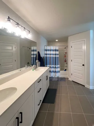 Dual vanity with integrated sinks, white cabinetry, and contemporary black hardware