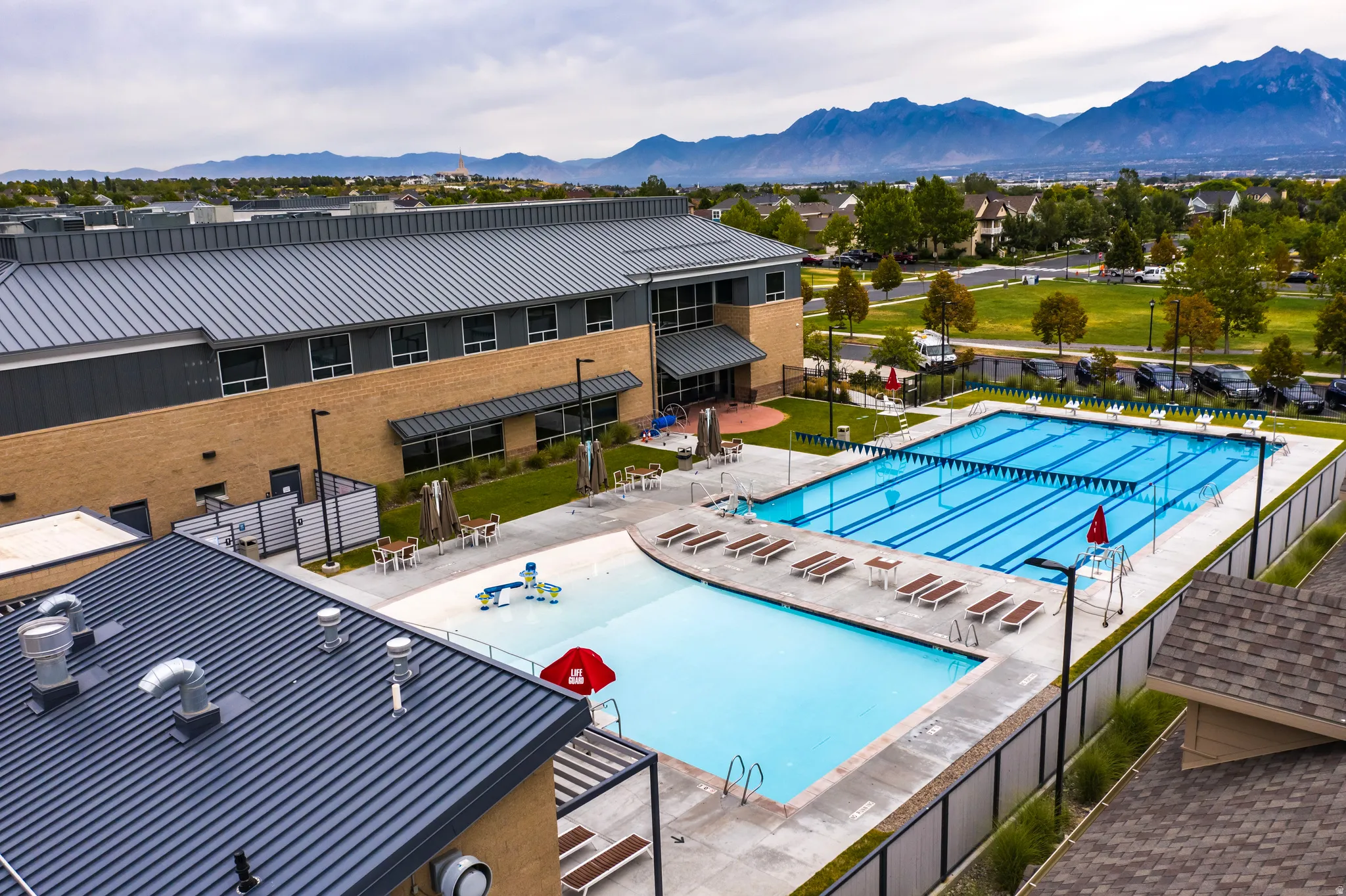 Expansive community pool area featuring a multi-lane lap pool, a separate recreation pool, and a surrounding concrete deck