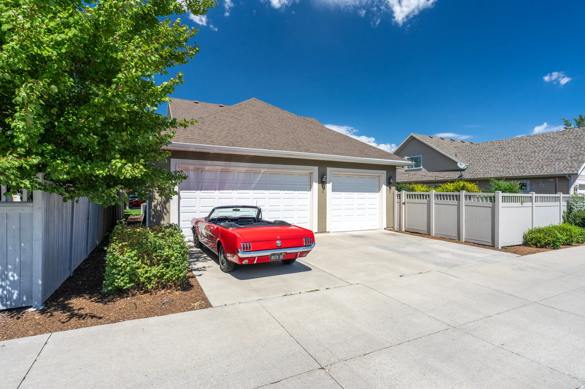 Exterior featuring a two-car garage, concrete driveway, and a partially visible private fence