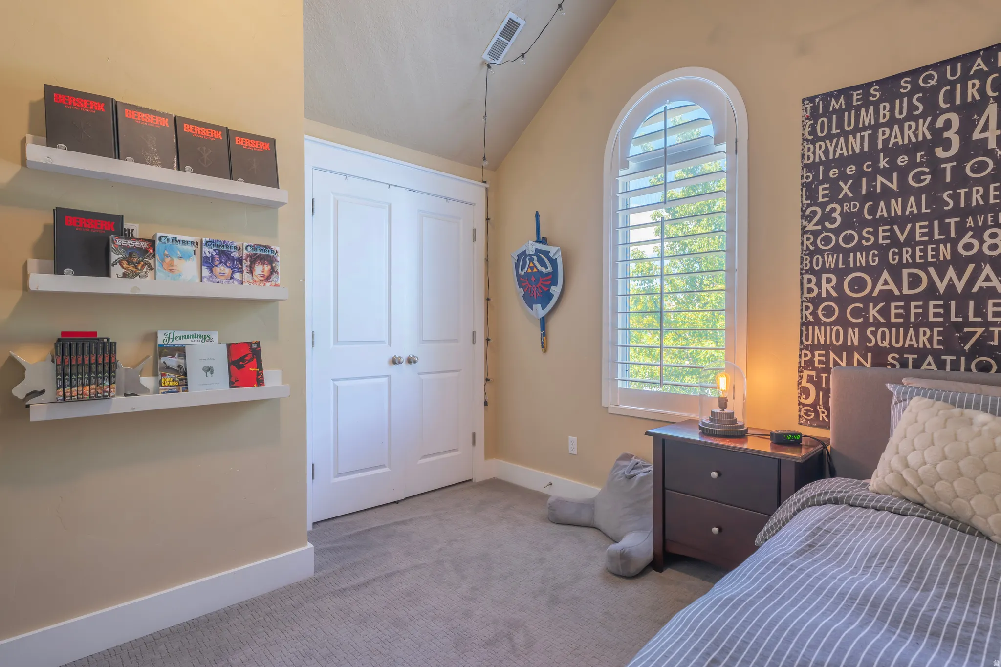 Arched window with plantation shutters, built-in shelving, plush carpet, and bi-fold closet doors