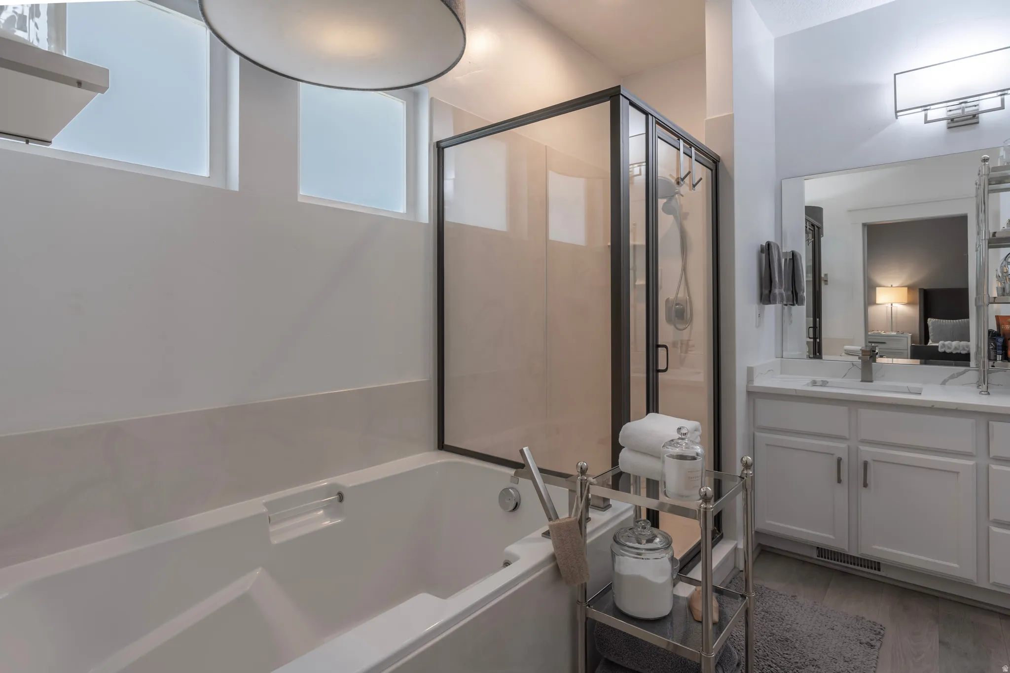 Freestanding soaking tub with a glass-enclosed shower, dual vanity with undermount sinks, and tiled flooring